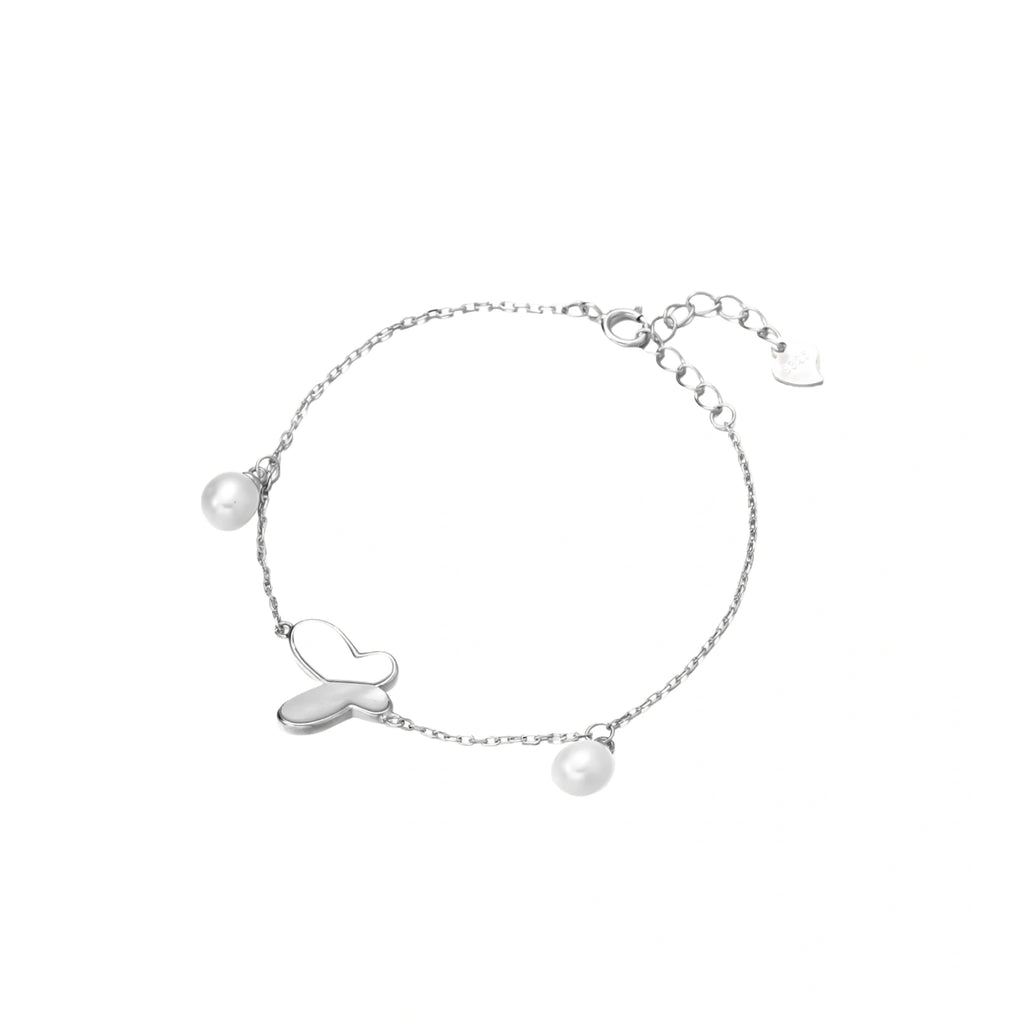 Delicate rhodium-plated silver chain bracelet with butterfly charm and two freshwater pearls on cream background