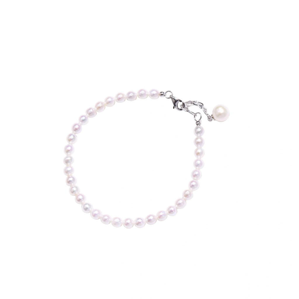 Adjustable bracelet featuring lustrous freshwater pearls with rhodium-plated sterling silver clasp on cream background.