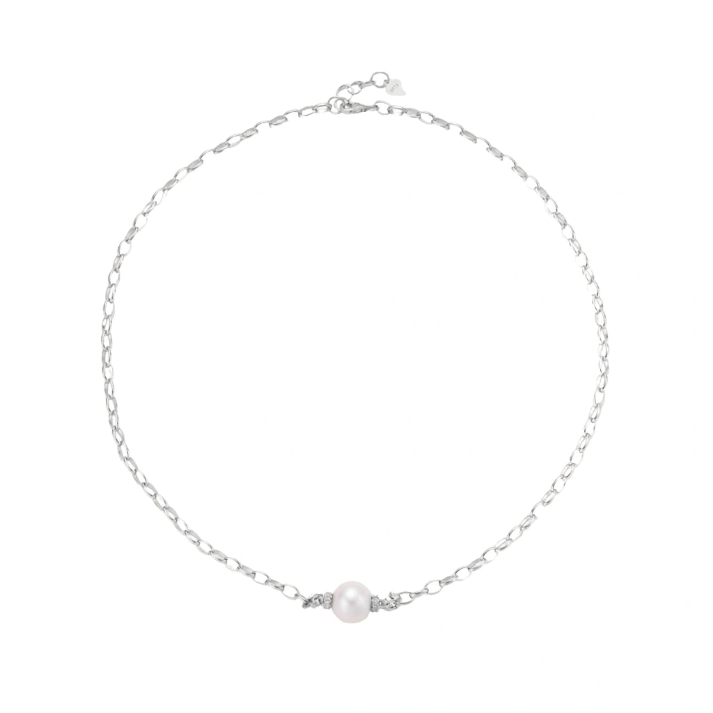 Dainty rhodium-plated silver chain necklace with centered 10mm freshwater pearl and crystal accents on cream background