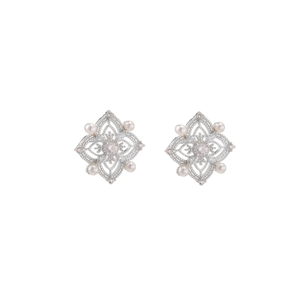 Ornate sterling silver stud earrings with mandala-inspired filigree pattern and four freshwater pearls on beige background