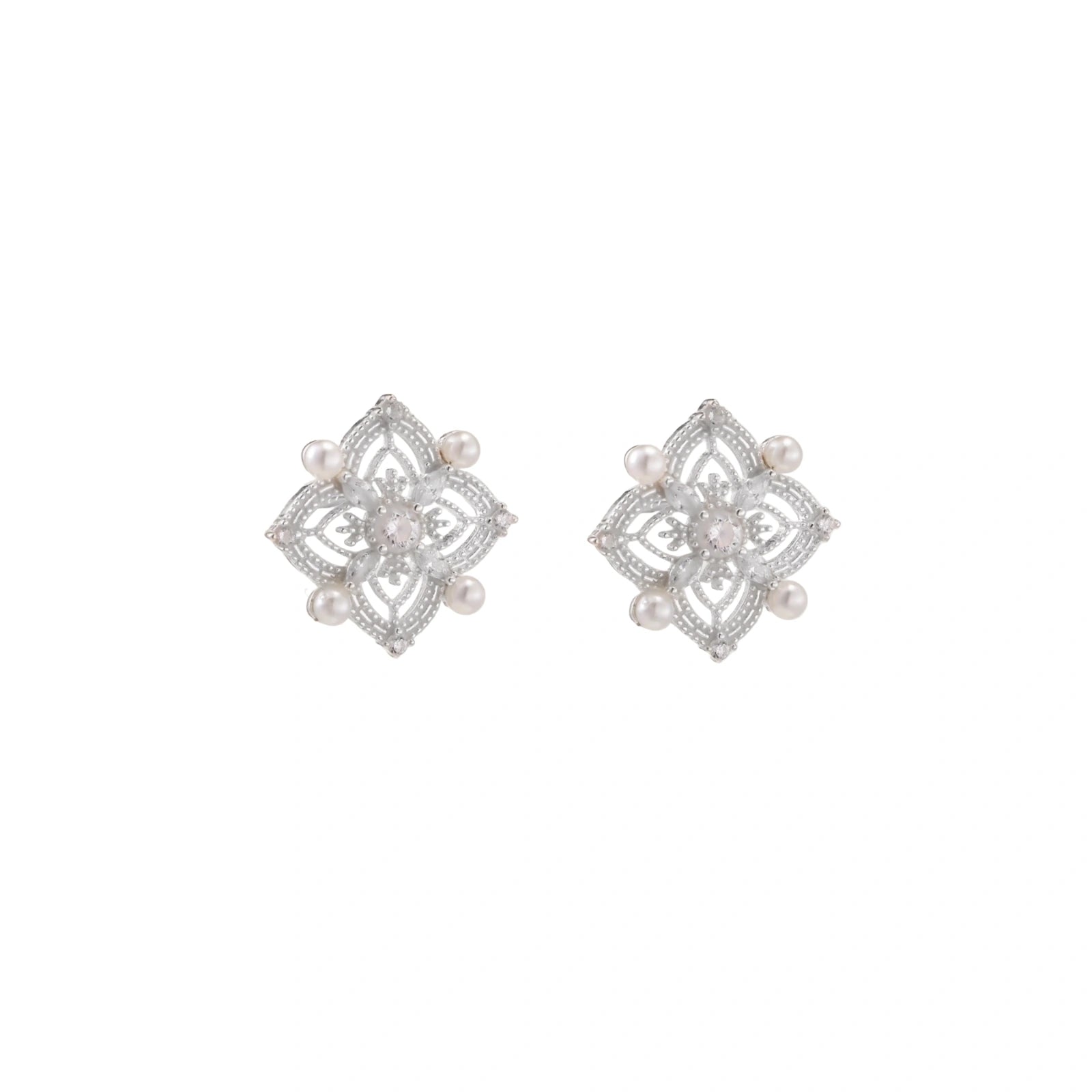 Ornate sterling silver stud earrings with mandala-inspired filigree pattern and four freshwater pearls on beige background