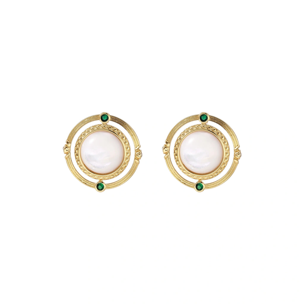 Circular gold stud earrings with iridescent mother-of-pearl center and green zirconia accents on cream background.