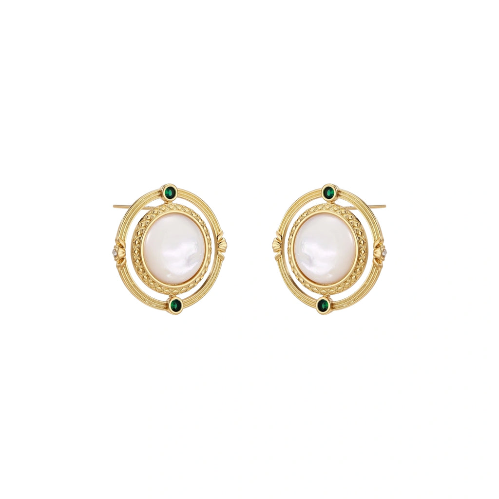 Circular gold stud earrings with iridescent mother-of-pearl center and green zirconia accents on cream background.