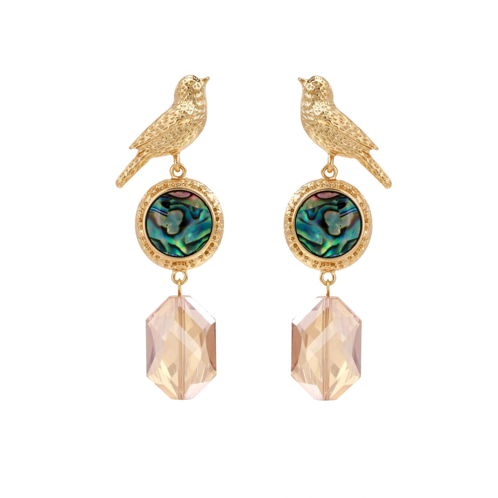 Gold-plated bird stud earrings with iridescent abalone shell medallions and champagne crystal drops on cream background