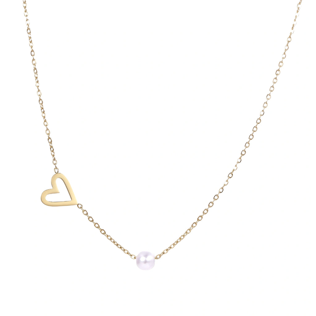 Delicate gold necklace with open heart charm and white pearl bead on fine chain against cream background