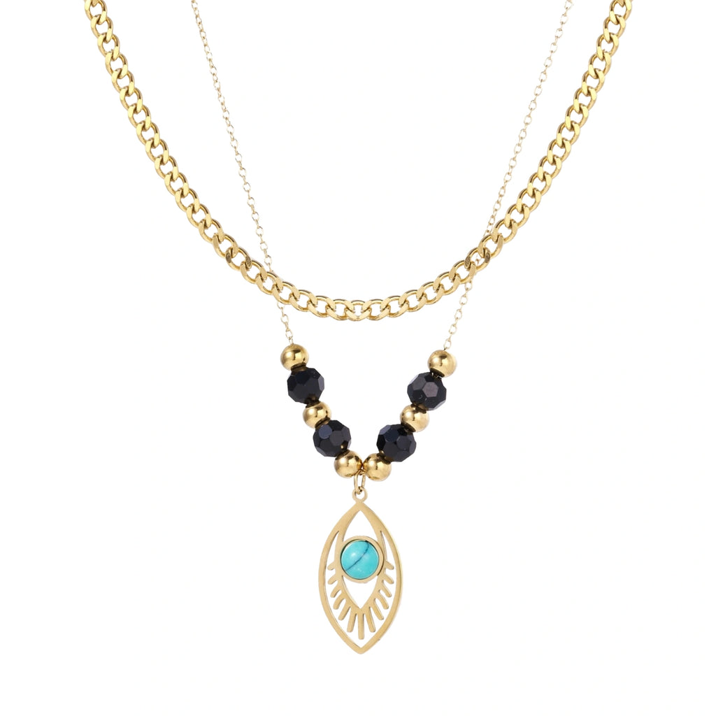 Layered gold necklace with turquoise evil eye pendant and black quartz beads on cream background