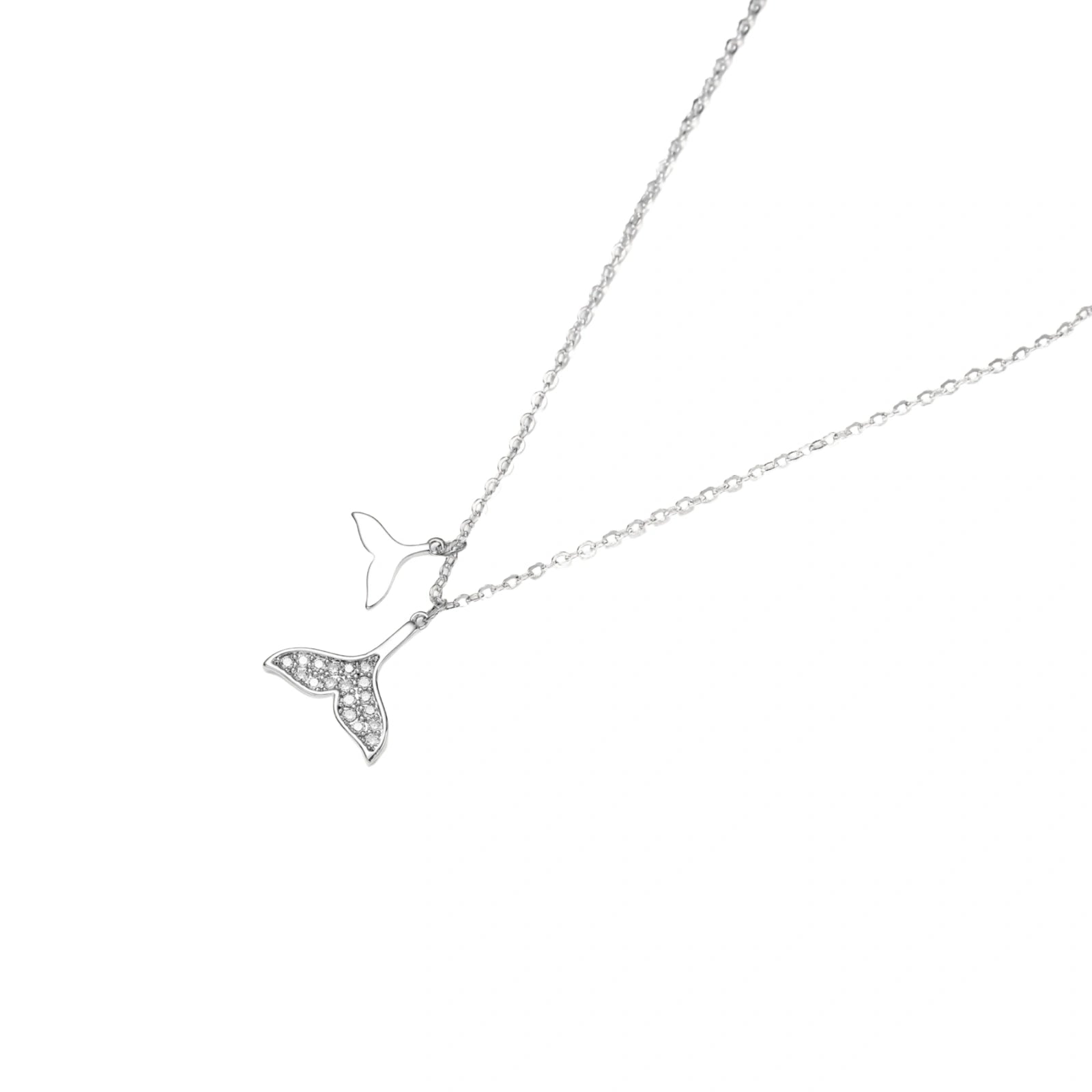 Delicate white gold plated whale tail pendant with pavé crystals on silver chain against cream background.