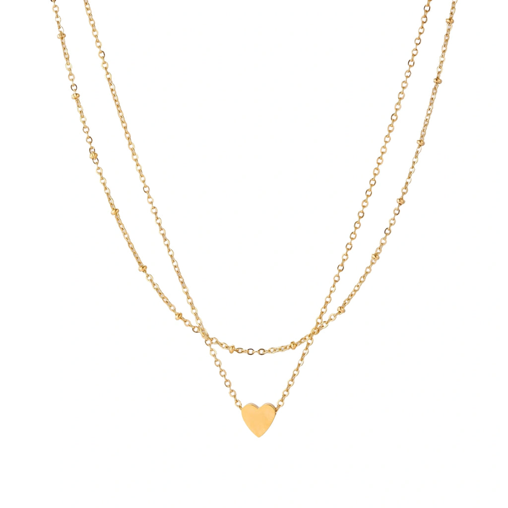 Delicate double-chain gold necklace with tiny heart pendant on cream background