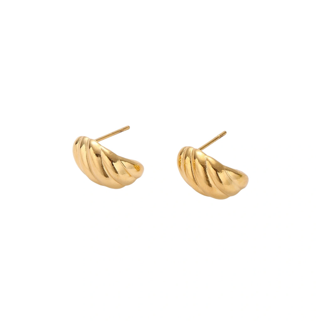 Chunky gold twisted rope huggie hoops with diagonal grooves and high-polish finish on cream background