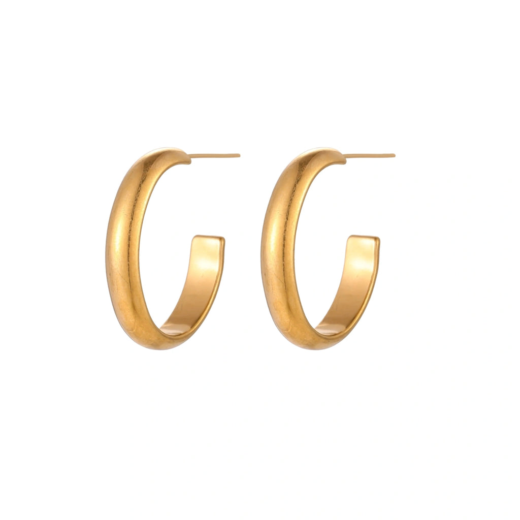 Chunky tubular hoop earrings in warm 14K gold-plated finish with smooth polished surface on cream background.