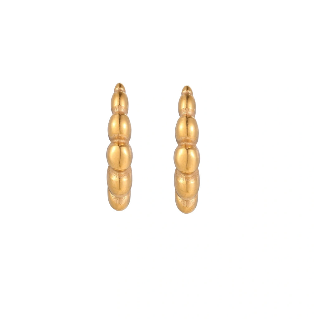Gold-plated chunky hoop earrings with ridged bubble texture on cream background