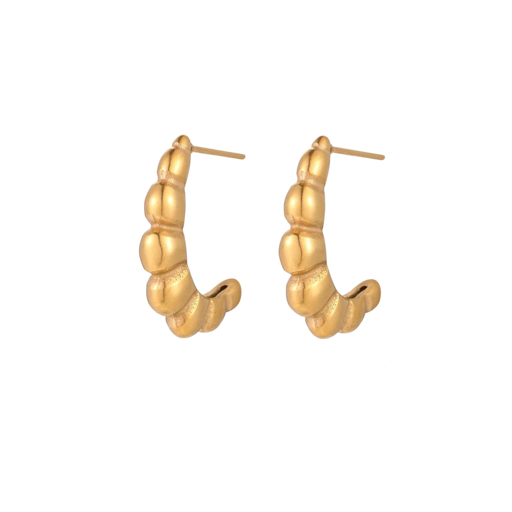 Gold-plated chunky hoop earrings with ridged bubble texture on cream background