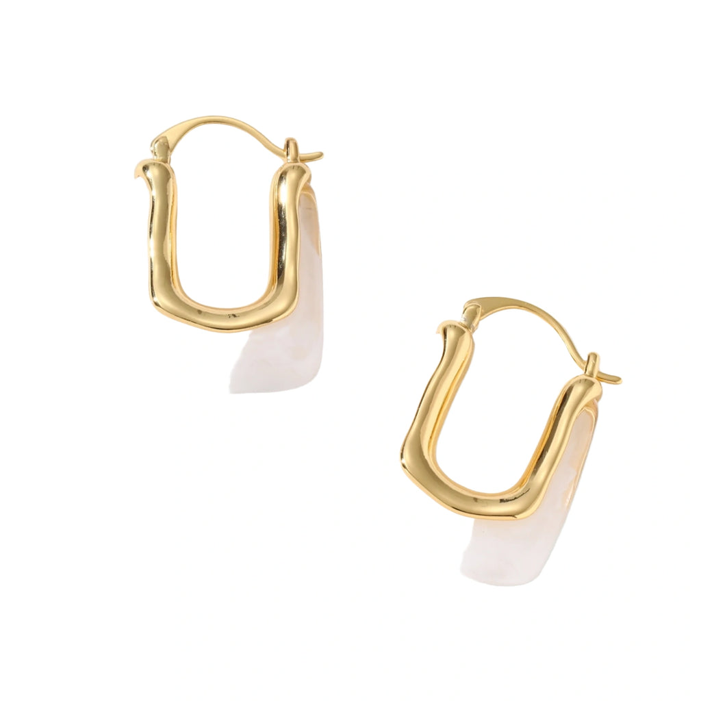 Sculptural gold-plated hoop earrings with flowing curved design and lever-back closure on cream background.