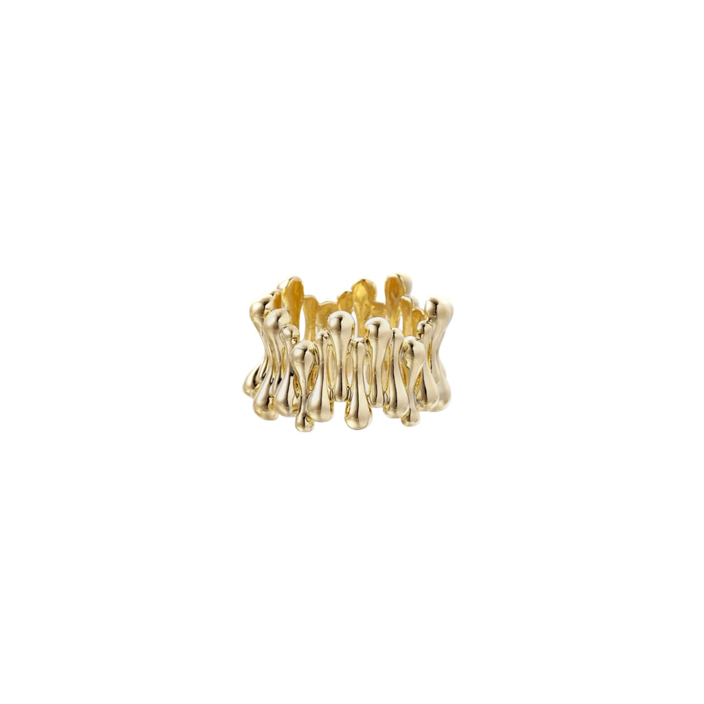 Gold-plated brass ring with sculptural petal-like elements in a wide band design on beige background
