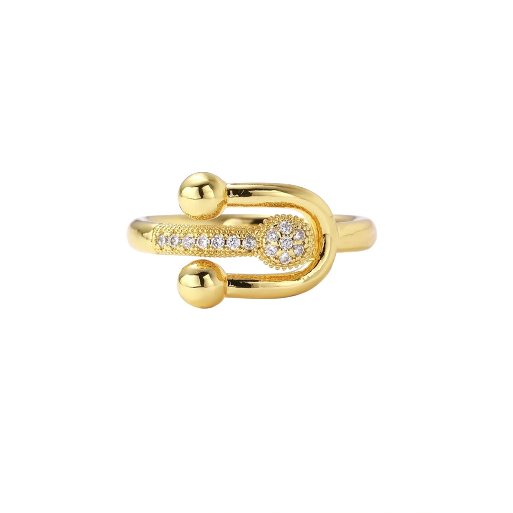 Gold-plated brass ring with safety pin design featuring pavé cubic zirconia stones and dual sphere ends