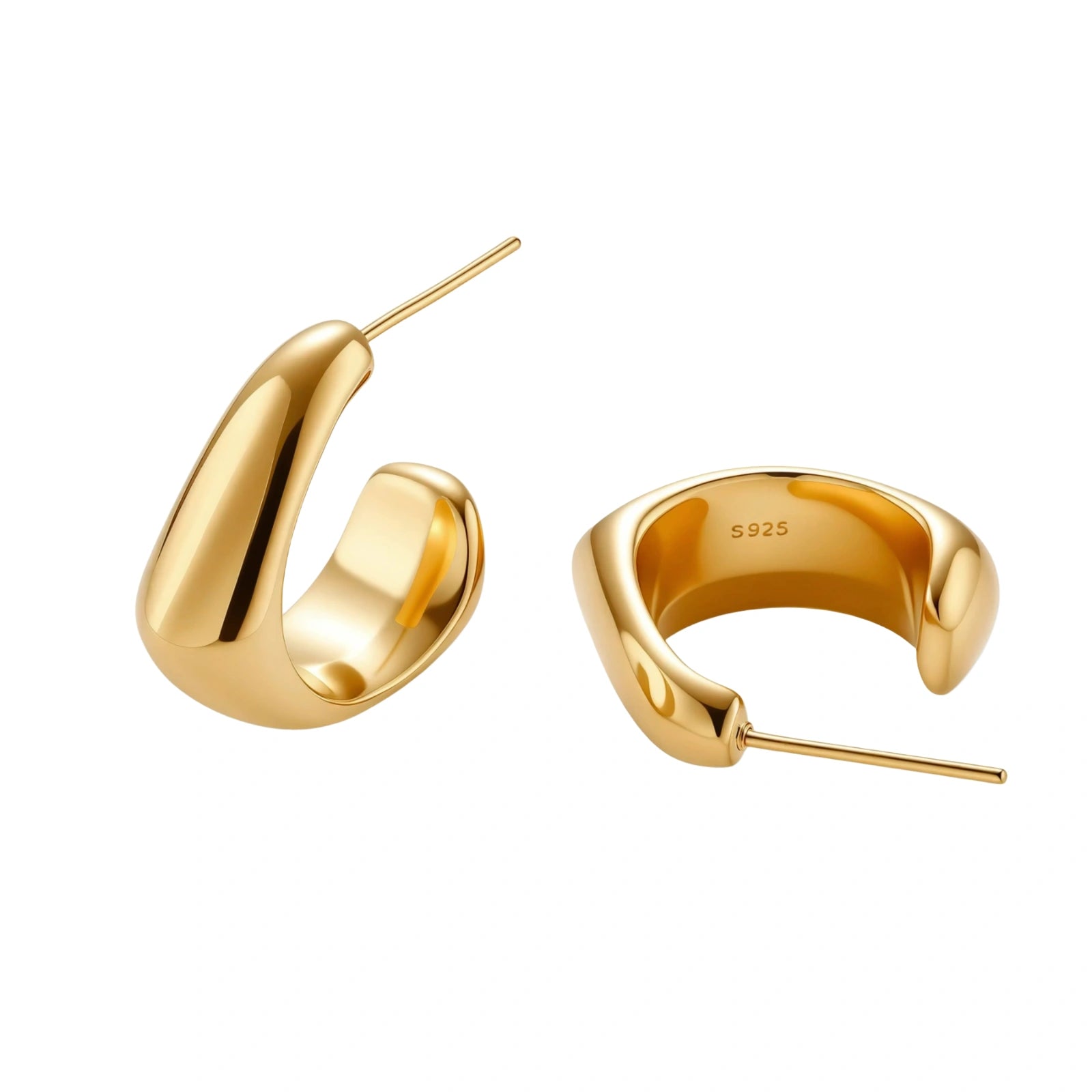 Close-up of curved gold-plated huggie earrings with sculptural design on white background, showing polished finish.