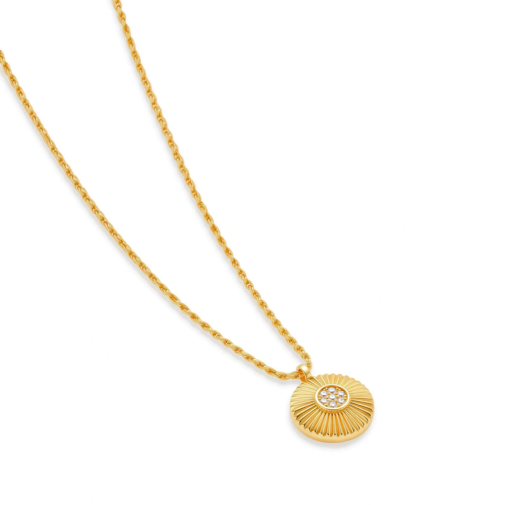 Gold-plated sterling silver necklace with sunburst pendant featuring radiating lines and cubic zirconia center stones