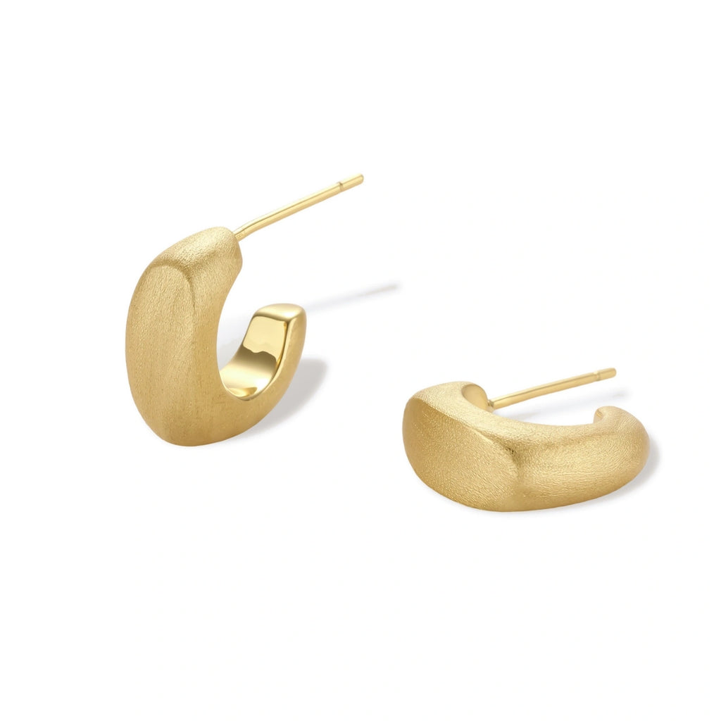 Small gold huggie earrings with matte finish, 14mm diameter, shown against cream background for everyday elegance.